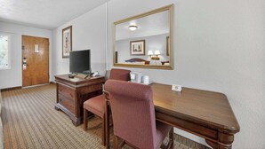 A hotel room with a wooden desk, a television, a mirror, a chair, and a dresser. - Eagle Motel Suite 118 (Manitou Springs)