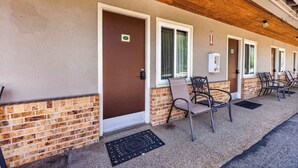 A building with multiple doors, a brick lower section, and outdoor seating with chairs. - Eagle Motel Suite 114 (Manitou Springs)