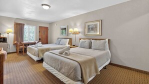 A hotel room with two beds, a desk, a chair, and a window with curtains. - Eagle Motel - Suite 116 (Manitou Springs)