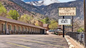 A motel with a mountain backdrop, a sign indicating self-check-in, and a vacant sign. - Eagle Motel - Suite 116 (Manitou Springs)