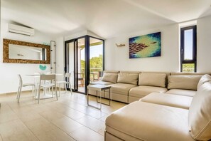 Ein modernes Wohnzimmer mit einer Couch, einem Esstisch mit Stühlen, einem kleinen Couchtisch, einem großen Spiegel und einem Gemälde an der Wand.