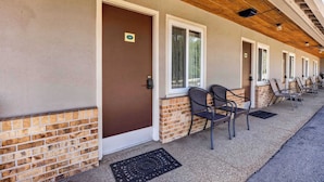 A building with a brown door, numbered room 117, and a row of chairs outside. - Eagle Motel Suite 117 (Manitou Springs)