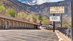 A motel with a mountain backdrop, a sign indicating self-check-in, and a vacant sign. - Eagle Motel Suite 117 (Manitou Springs)