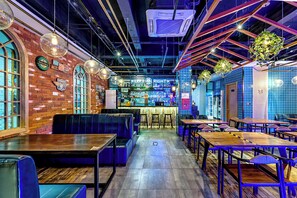 A restaurant with brick walls, blue-tiled bar area, wooden tables, and blue booths. - Happy Dragon Saga Hotel (Beijing)