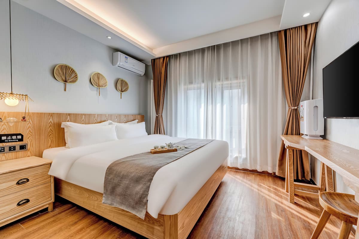 Una habitación de hotel moderna con una cama de madera, mesitas de noche, un escritorio y un televisor.