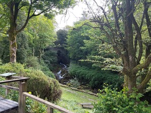A wooden deck with a bench, a small waterfall, and dense greenery. - Cross Winds (Lancaster)