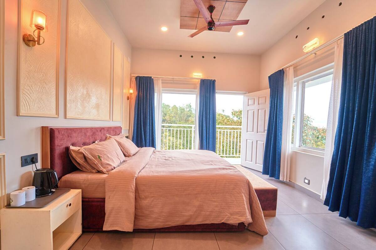A bedroom with a bed, a nightstand, a ceiling fan, and a window with curtains.