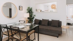 A modern living room with a glass dining table, dark brown sofa, and a large mirror. - Spectacular apartment (Cap d'Artrutx)