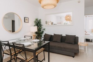 Een moderne woonkamer met een glazen eettafel, een donkerbruine bank en een grote spiegel.