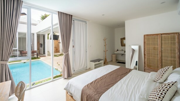 Un dormitorio con una cama grande, un escritorio, una silla, una mesita, un baño y una zona de piscina.