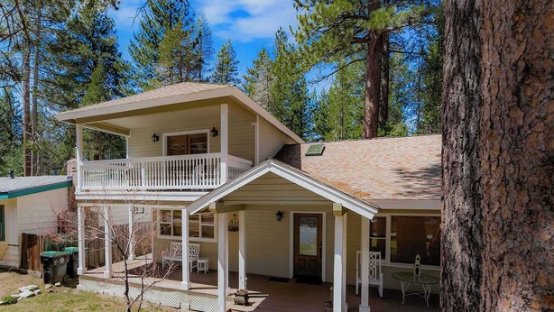 Una casa a due piani con un balcone, un portico e un piccolo giardino antistante.