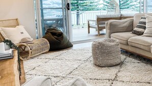 Ein modernes Wohnzimmer mit einer Couch, einem Sitzsack, einem Teppich und einem Korbstuhl.