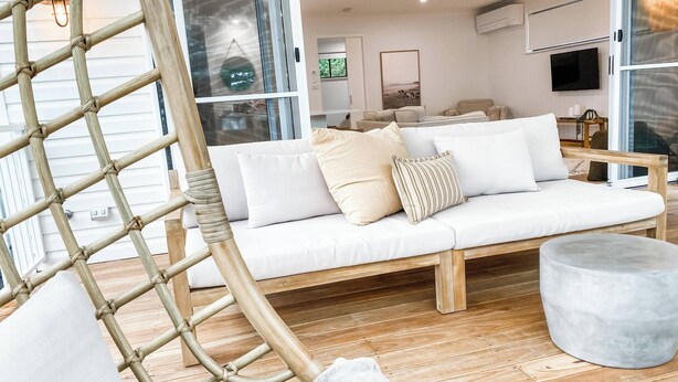 Ein modernes Wohnzimmer mit einem weißen Sofa, einer Holzbank und einem runden Ottomanen.