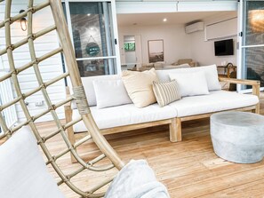 A modern living room with a white sofa, a wooden bench, and a round ottoman. - Morgies on Long Beach (Long Beach)