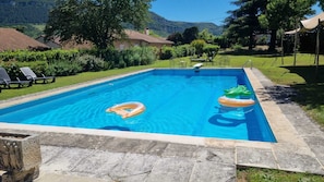 Una piscina rectangular con agua azul cristalina, rodeada por una terraza de piedra.