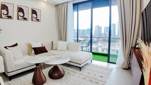 A modern living room with a white sofa, a round coffee table, and a large window offering a city view. - Ikhaya Luxe Westlands with Rooftop Heated pool, gym and amazing GTC view (Nairobi)