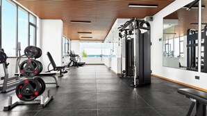 A gym with weightlifting equipment, exercise machines, and large windows.