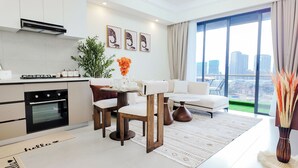 A modern kitchen with a gas stove, oven, and a dining area with a white sofa and a table. - Ikhaya Luxe Westlands with Rooftop Heated pool, gym and amazing GTC view (Nairobi)