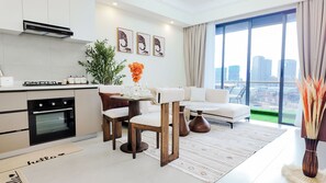 A modern kitchen with a gas stove, oven, and a dining area with a white sofa and a table. - Ikhaya Luxe Westlands with Rooftop Heated pool, gym and amazing GTC view (Nairobi)