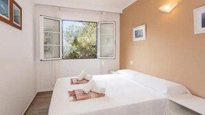 Ein Schlafzimmer mit einem Bett, einem Fenster und einer Wandleuchte.