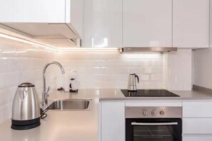 A modern kitchen with white cabinets, stainless steel appliances, and a built-in oven. - Beautiful apartment Bon Repos 8 (Cap d'Artrutx)