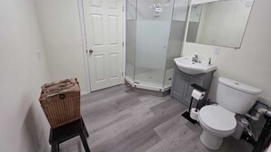A bathroom with a shower, toilet, sink, and a mirror. - Spacious 3 Bedroom Private Guest Suite (Inuvik)
