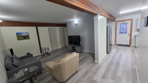 A modern living room with a sofa, television, and a small table. - Spacious 3 Bedroom Private Guest Suite (Inuvik)