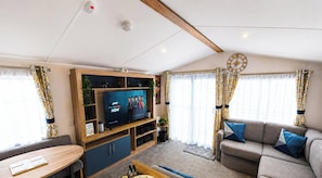 Ein modernes Wohnzimmer mit Flachbildfernseher, Holzbögen, einer Couch und Vorhängen.
