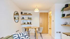 A modern living room with a dining table, chairs, a sofa, and a mirror. - The Fifth Above Hackney (London)