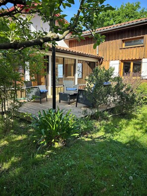 Una casa de madera con un porche cubierto, muebles de exterior y un jardín.