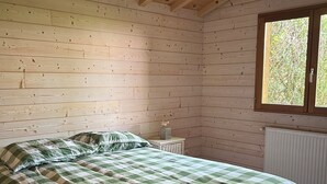 Een slaapkamer met een bed, houten wanden, een raam en een radiator.