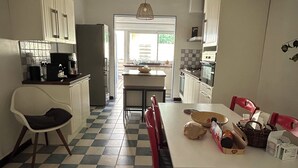 Een keuken met een zwart-wit geruite vloer, een eettafel met stoelen en een hanglamp.