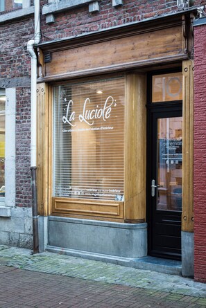 A storefront with a large window displaying the name 'La Luciole' and a black door. - House - Urban decor gîte, La Luciole, ideally located in the heart of the Ardennes, (Marche-en-Famenne)
