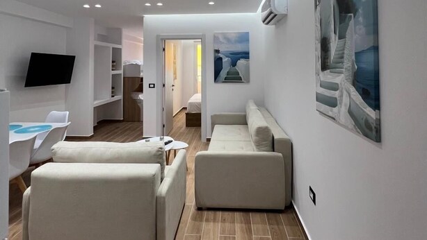 Una sala de estar moderna con una televisión de pantalla plana, un sofá, una mesa de centro y un cuadro en la pared.