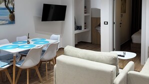 Una sala moderna con comedor, un televisor de pantalla plana montado en la pared y un cuadro de un árbol.