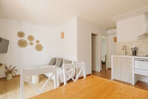 Ein modernes Wohnzimmer mit Sofa, Sesseln, Couchtisch und Küchenbereich, inklusive Geschirrspüler und gefliestem Fliesenspiegel.