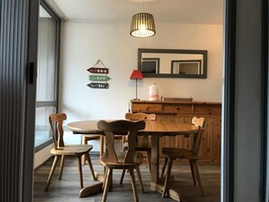 Ein Essbereich mit Holztisch und -stühlen, einer Hängeleuchte, einem Spiegel und Hinweisschildern an der Wand.