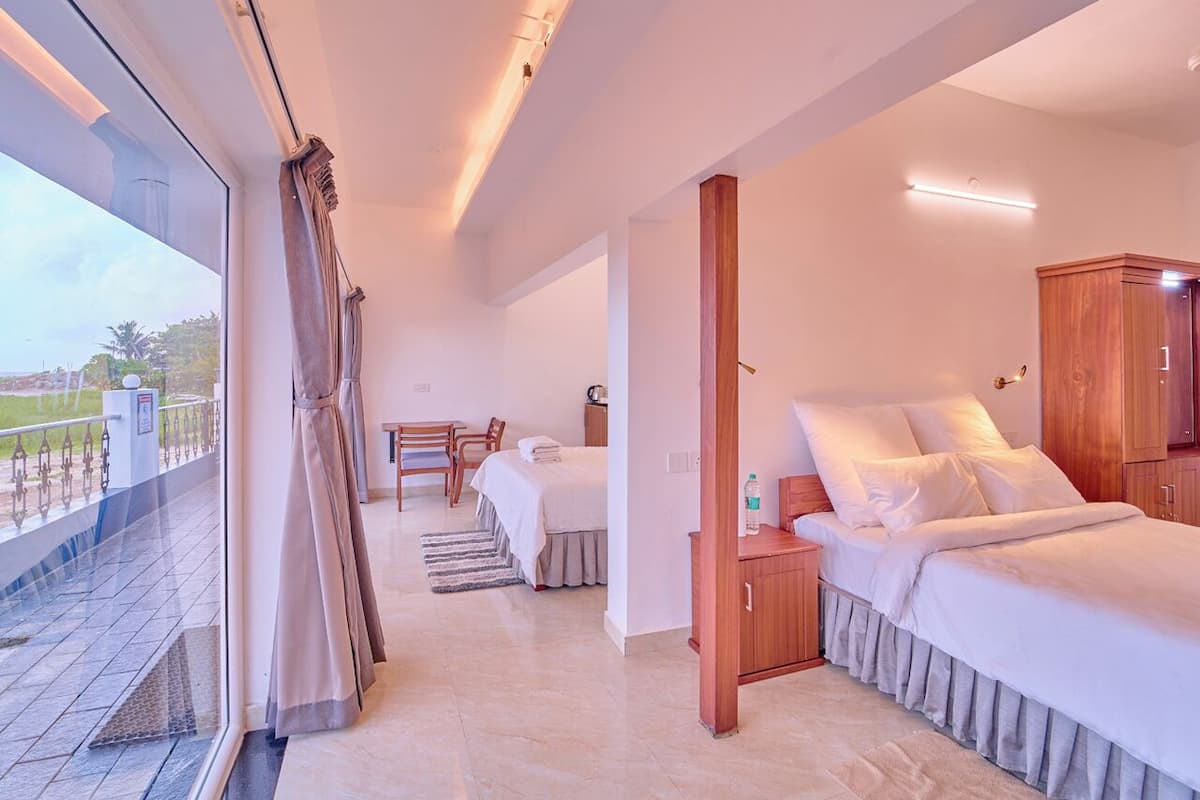 A hotel room with a balcony, a bed, a desk, and a wardrobe.