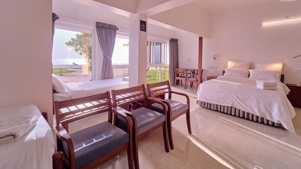 Ein Hotelzimmer mit Bett, Schreibtisch und Blick auf den Strand.