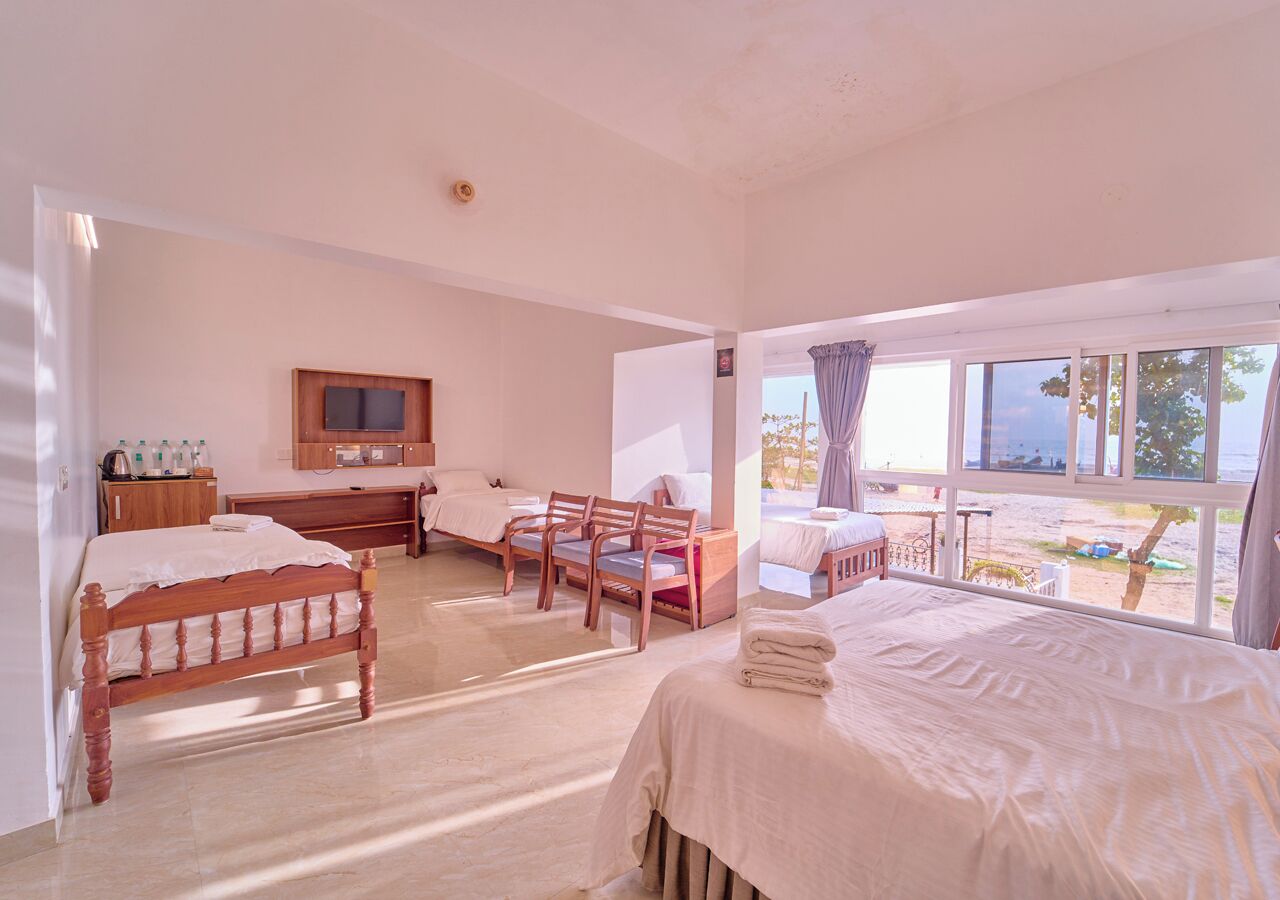 A bedroom with two beds, a TV, a desk, and a chair.