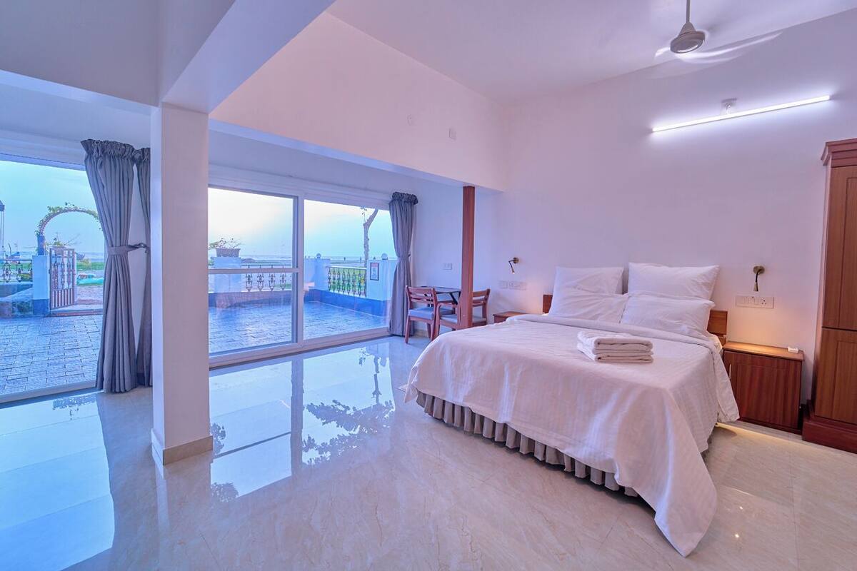 A modern hotel room with a large bed, a view of the pool, and a balcony.