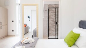 Een hotelkamer met een bed, een kledingkast, een spiegel en een deur die naar een andere kamer leidt.