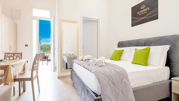 Een hotelkamer met een bed, een eethoek en uitzicht op de omgeving.