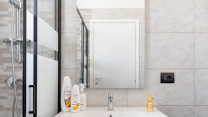 Une salle de bain avec une douche à parois de verre, un lavabo blanc et un miroir au-dessus.