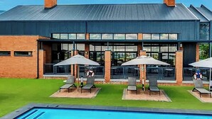 Um edifício com piscina, área de estar externa e céu azul límpido.