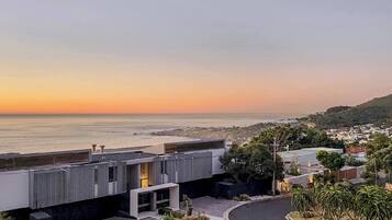 A modern building with a view of the ocean at sunset.