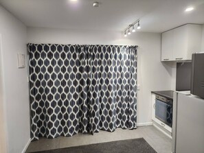 A kitchen with a patterned curtain, a refrigerator, and a stove.