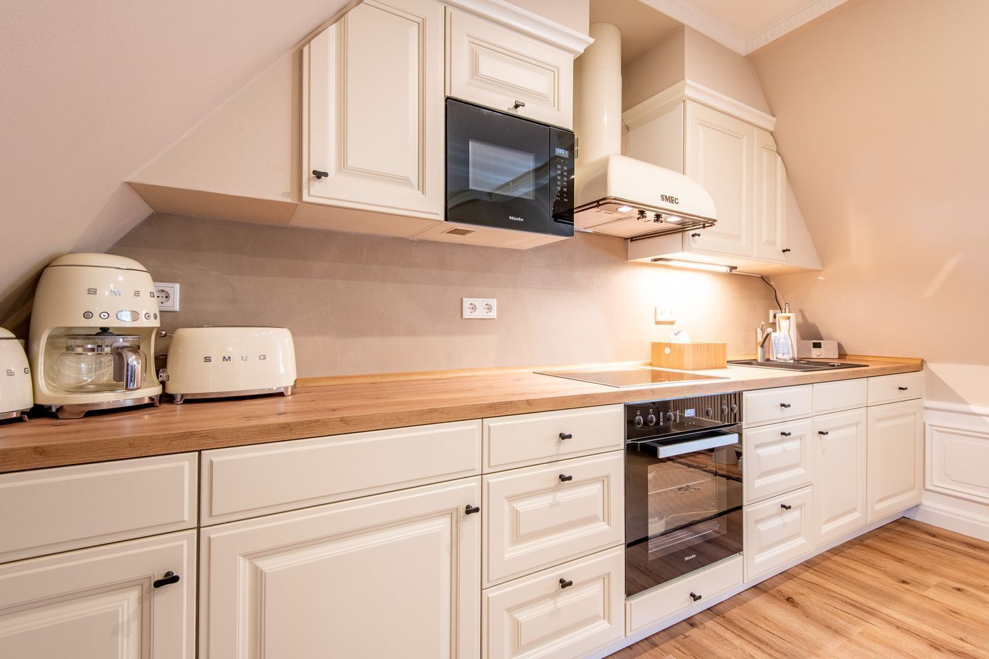 A kitchen with white cabinetry, a microwave, a toaster, a coffee maker, and an oven.