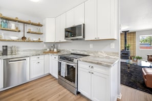 A modern kitchen with white cabinets, a stainless steel dishwasher, a built-in oven, and a microwave. - Outside Inn - Pacific Grove House - Downtown - Close to Beach (Pacific Grove)