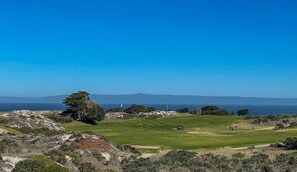A golf course with a clear view of the ocean and distant mountains. - Outside Inn - Pacific Grove House - Downtown - Close to Beach (Pacific Grove)